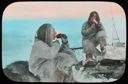 Image of Eskimos [Inuit] Cutting Meat Off at Lips